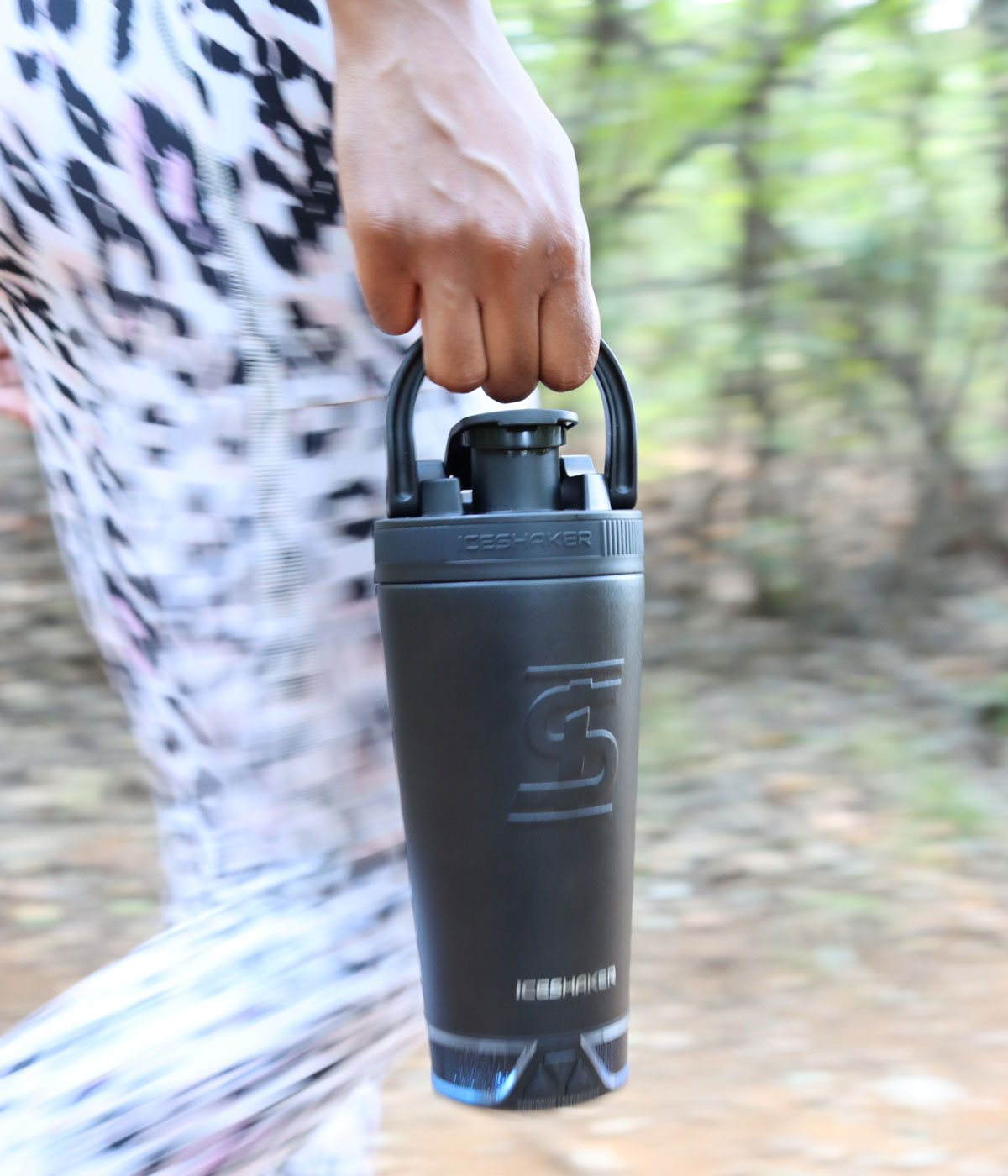 an image of the black 20oz Speaker Bottle being held by it's handle that's built into the lid. The speaker is lighting up blue which indicates that it is on.