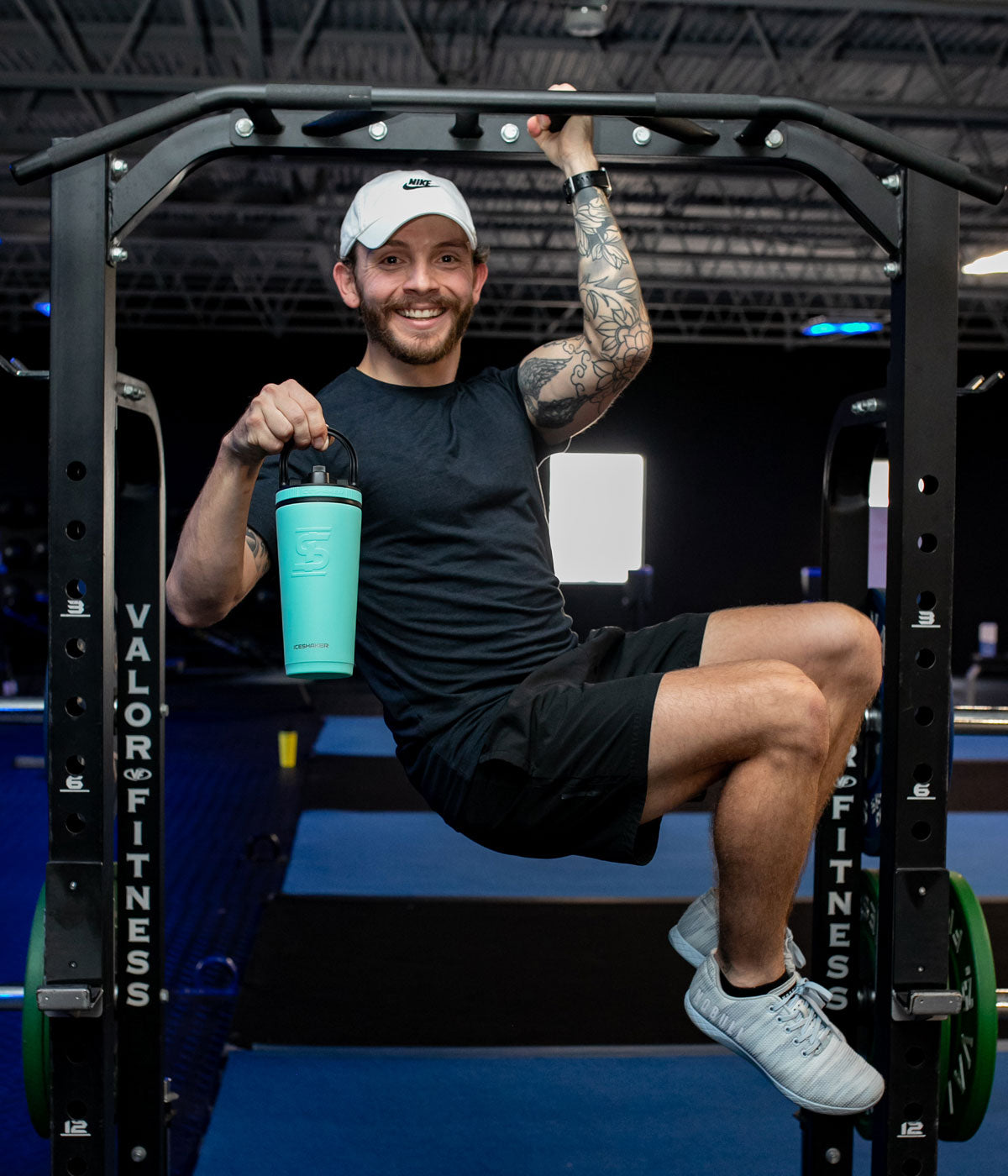 This image shows a young, happy man doing a one-armed pull up while he is holding the mint-colored 26oz Sport Bottle in his other hand.