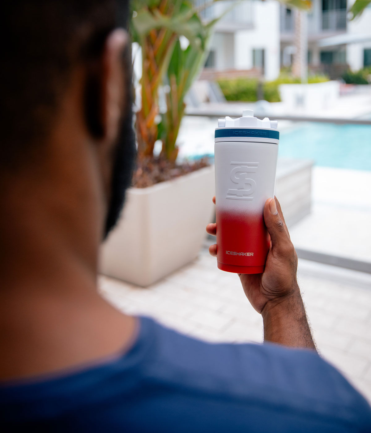 An image of a man holding the USA-colored 26oz Sport Bottle. There is a pool in the background of the image.