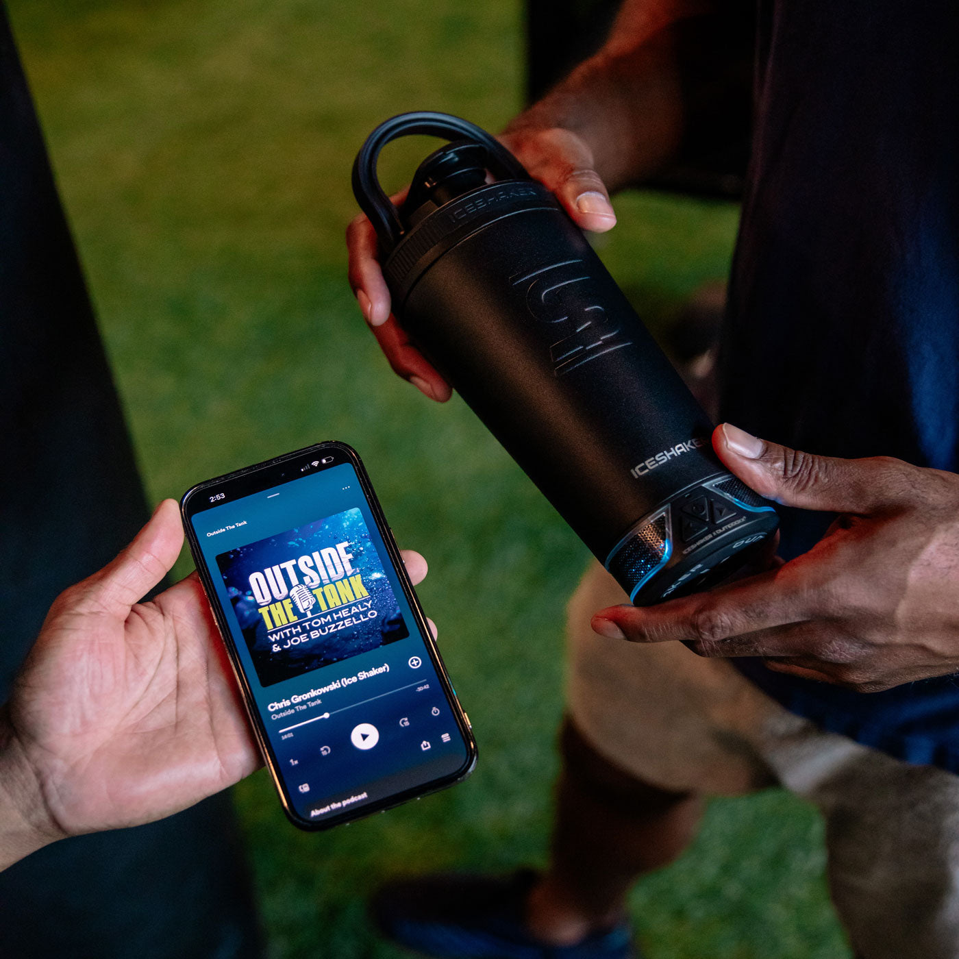 An image of the Black 20oz Speaker Bottle being paired by Bluetooth to a iPhone. On the Iphone, it is playing the Outside the Tank podcast.