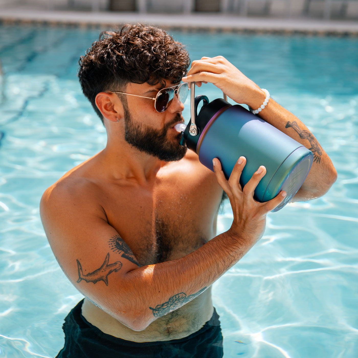 An image of a man standing in a pool, taking a drink from a Wisteria-colored Half Gallon Jug.