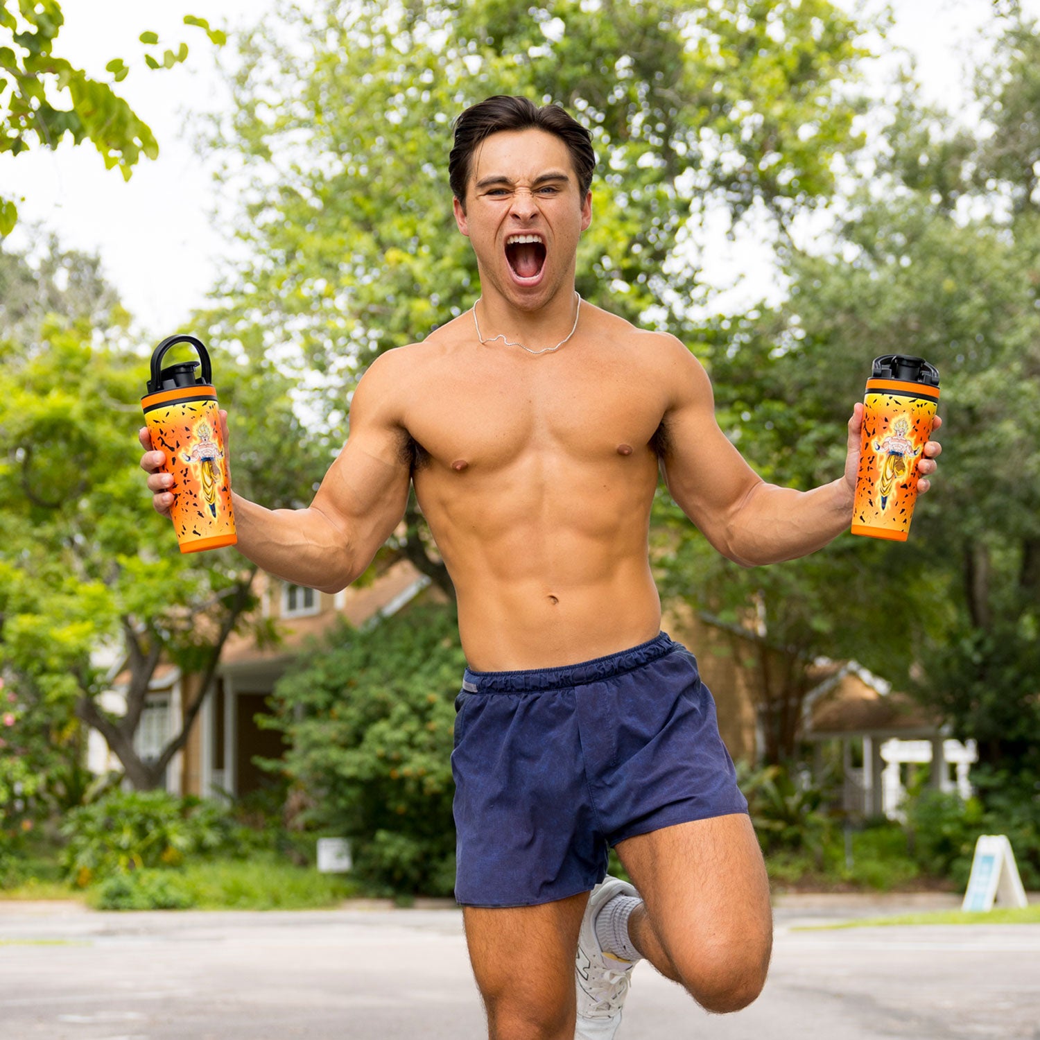 Man running outdoors holding two Dragon Ball Z Goku 26oz Ice Shakers with an excited expression on his face.