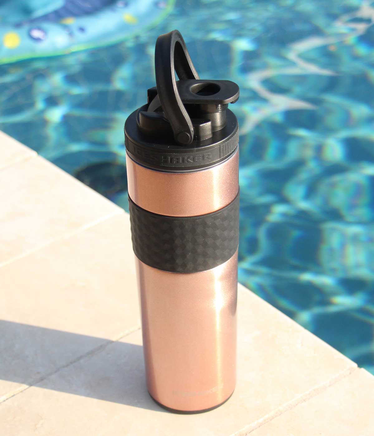 An image of the Rose Gold 20oz Skinny Shaker. It's sitting by a pool on a sunny day.
