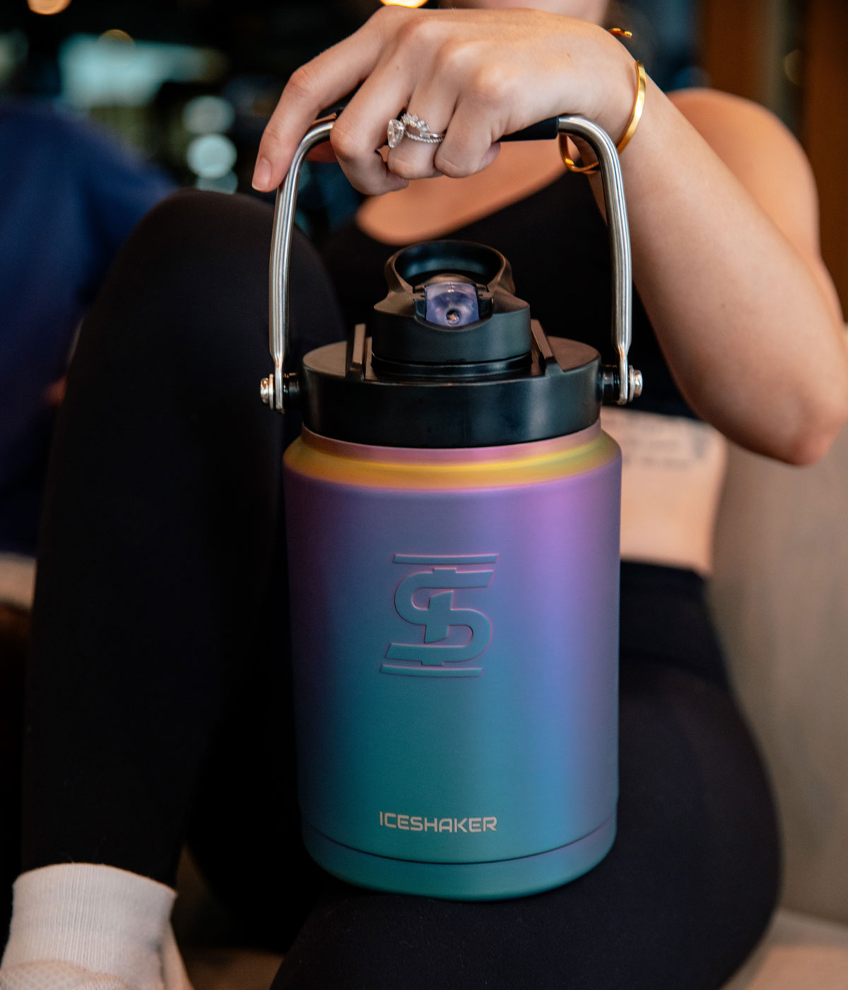 A woman's hand with a ring on it holds a Wisteria-colored Half Gallon Jug in her lap.