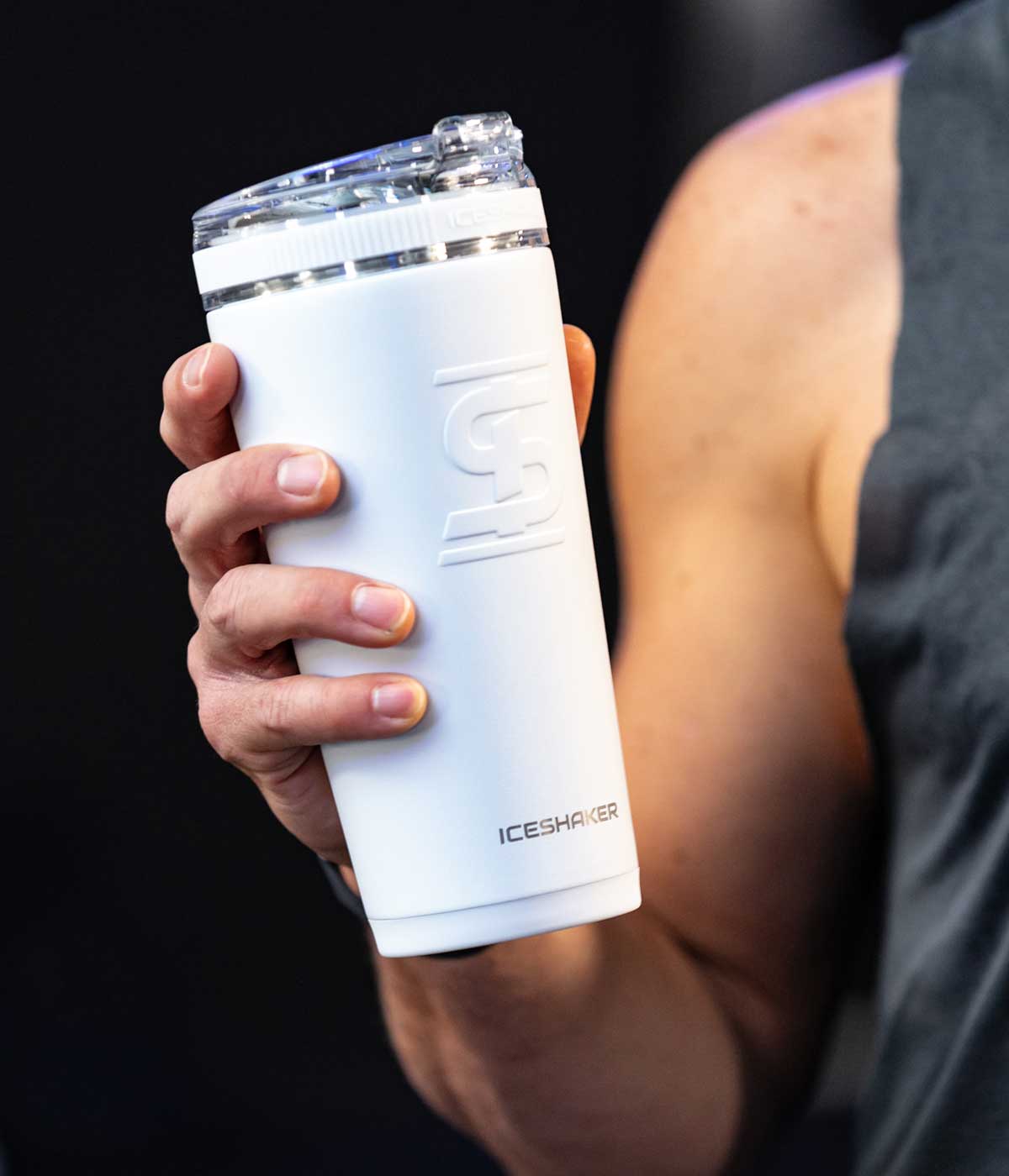 This image shows a close-up image of the White 26oz Flex Bottle being held by a hand. There is a man's muscley arm in the background