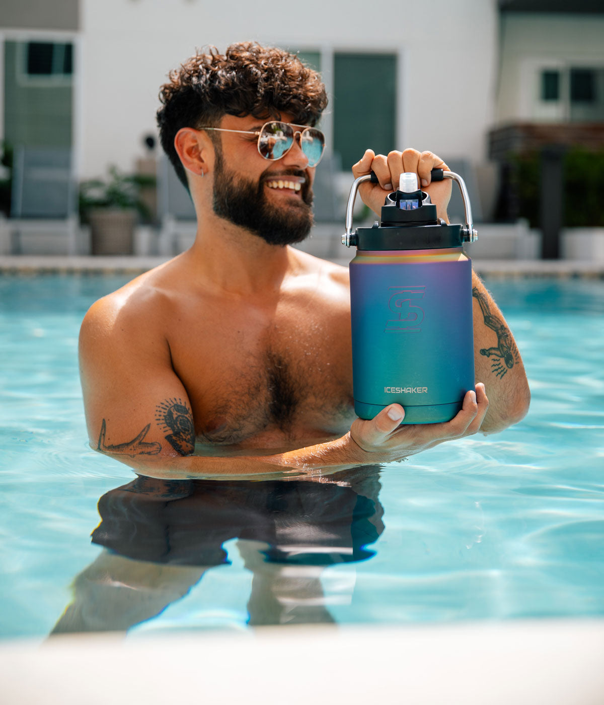 A young man in a pool with sunglasses on holds a Wisteria-colored Half Gallon Jug.