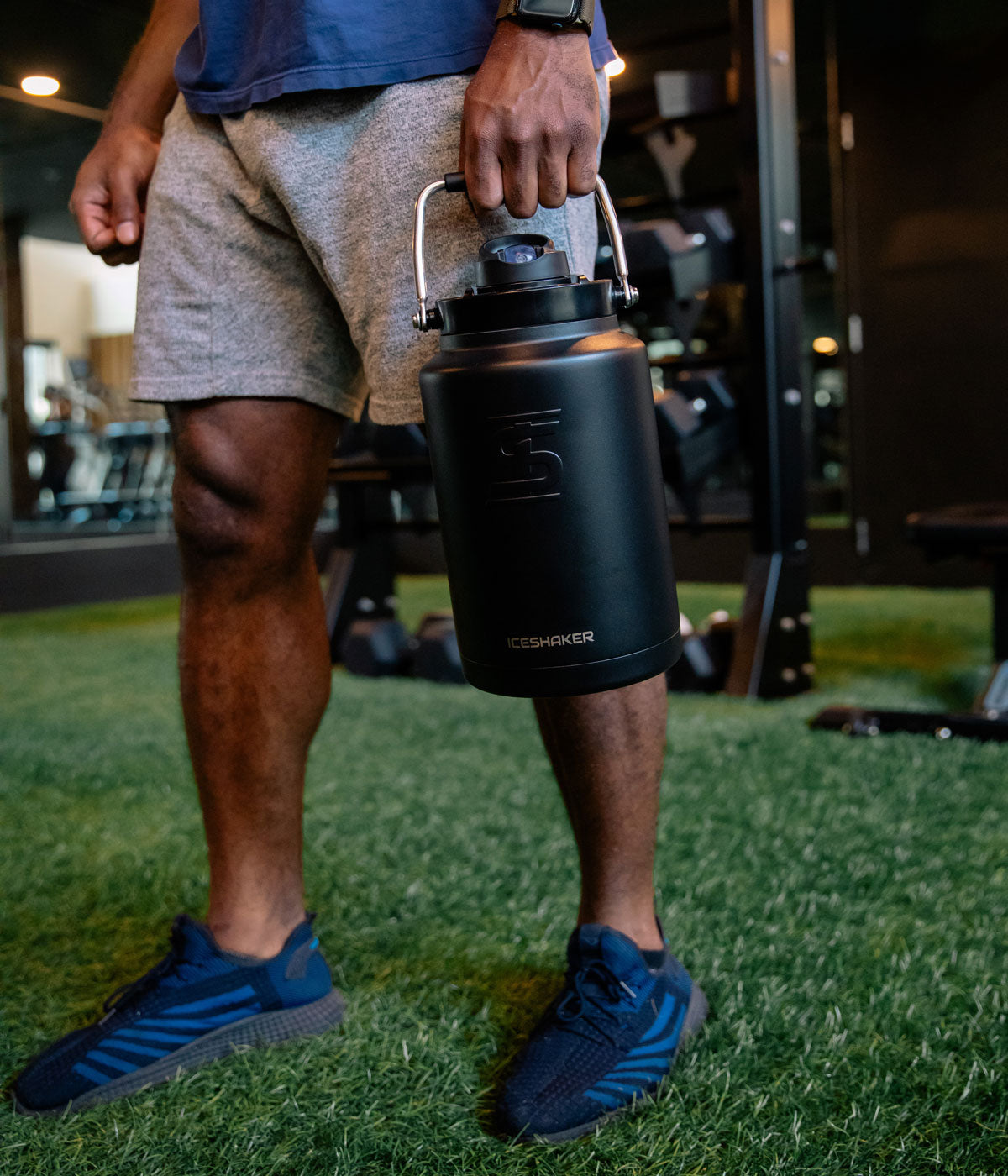 A man holds a Black-colored One Gallon Jug by it's easy-carry handle.