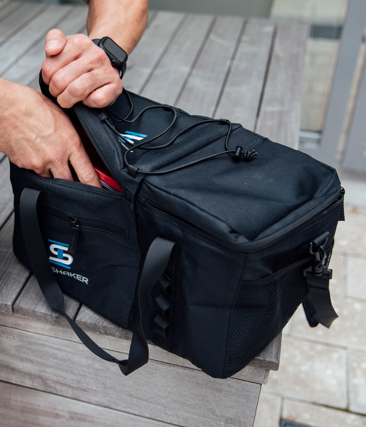 This image shows a close up view of the The Duffel as a hand inserts a food container into The Duffel Bag.