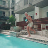 This 8-second long video shows a man holding a Navy Mint Ombre-colored Ice Shaker Jug as he runs and jumps into a pool. The Jug is then seen floating on water, then on the side of a pool. The man in the video removes the inner jug lid and pours water from the jug into a cup.