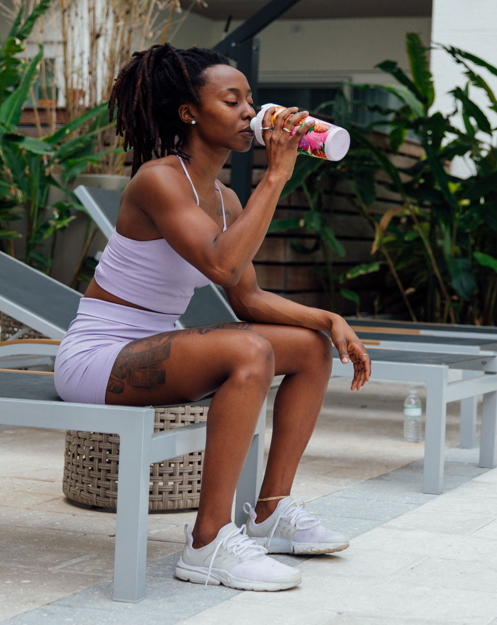an image of a woman in workout attire, sitting on a bench, taking a refreshing drink of water from an insulated Ice Shaker bottle