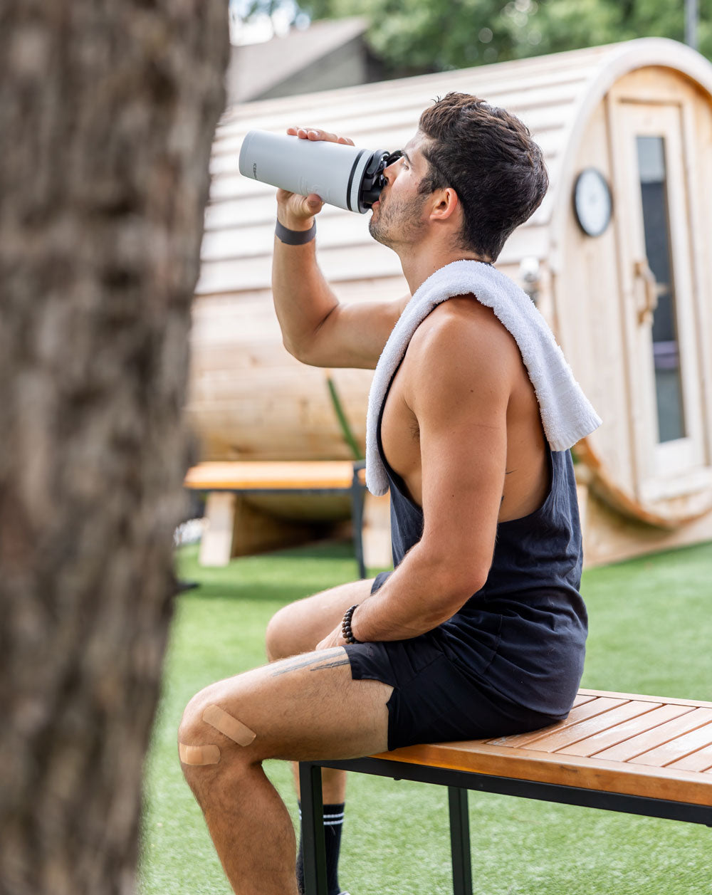 an image of a man sitting outdoors drinking water from an insulated Ice shaker Bottle