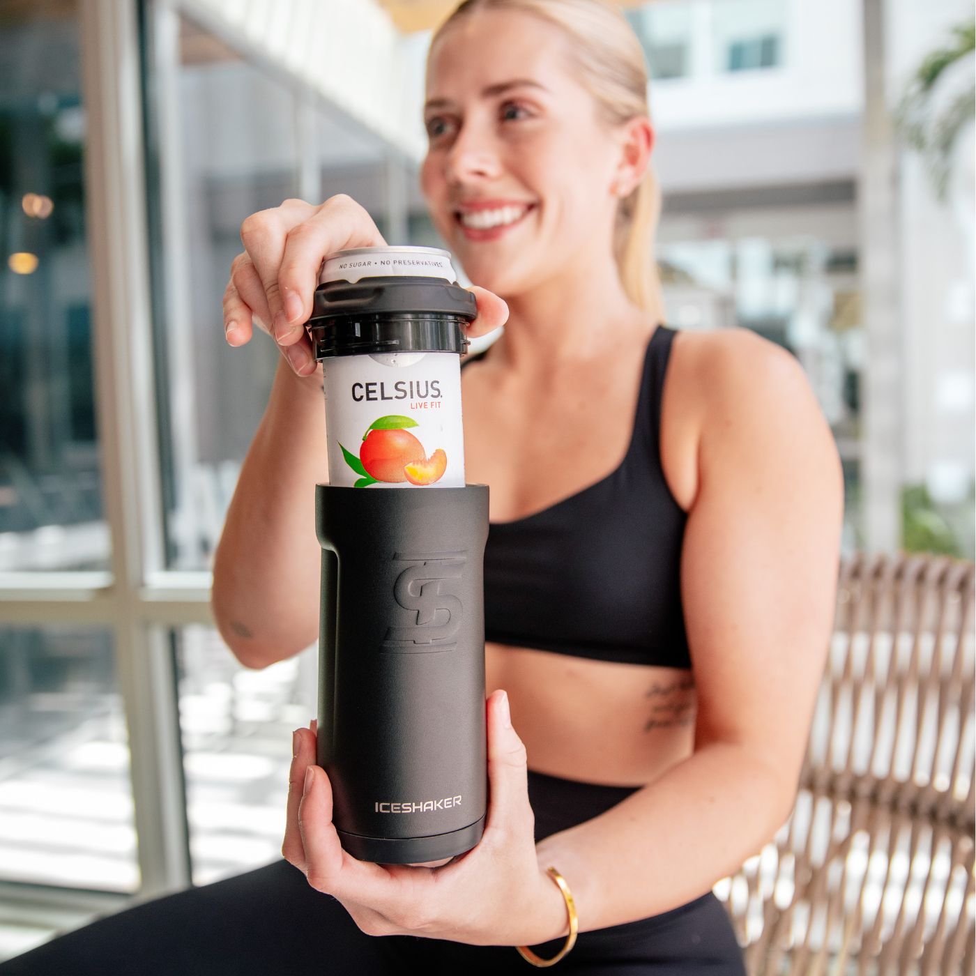 This image shows the same young, athletic woman placing the top rubber lip back onto the Canpanion. The top rubber lip is easily sliding over the slim 12oz Celsius can.