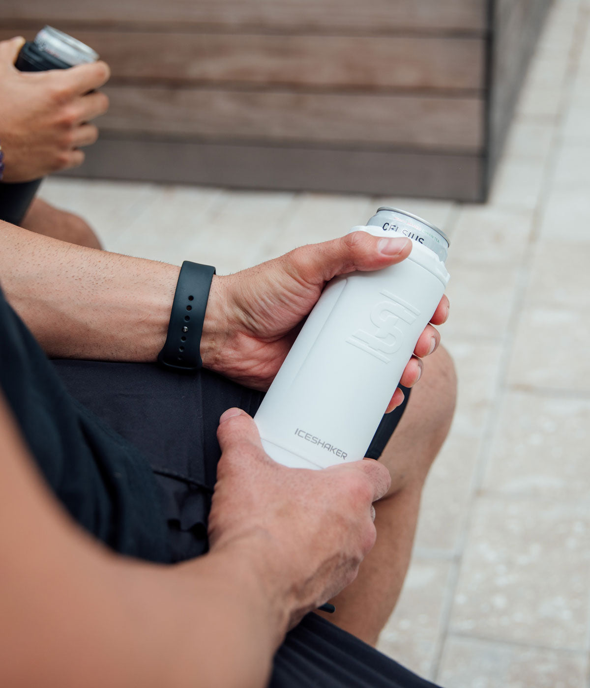 A close-up image of a man holding a white 12oz Canpanion with a can inserted in it.