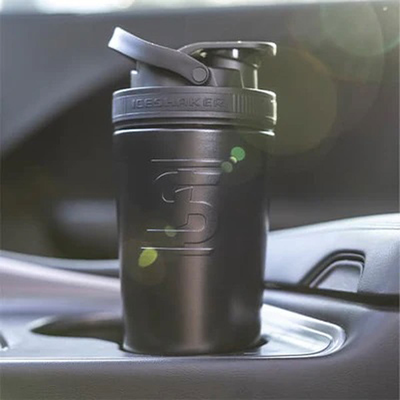 This image shows a Black 26oz Ice Shaker fitting easily into a car's cup holder.