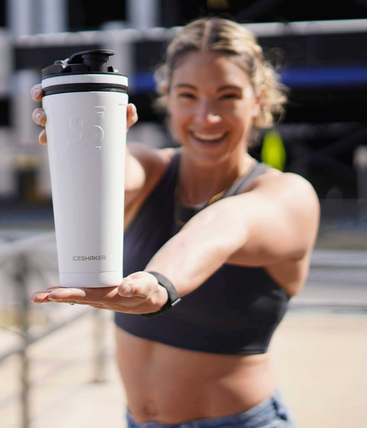 An excited, cheerful girl holds out the white-colored 36oz Ice Shaker in front of her. 
