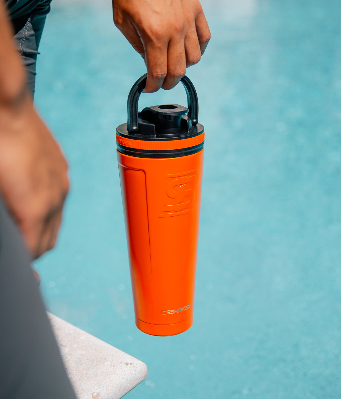 The orange-colored 36oz Ice Shaker is being carried by it.s handle that conveniently built into the lid of the 36oz Ice Shaker