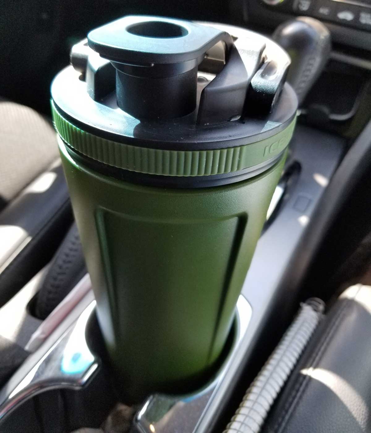 A green-colored 36oz Ice Shaker fitting in a car's cup holder.
