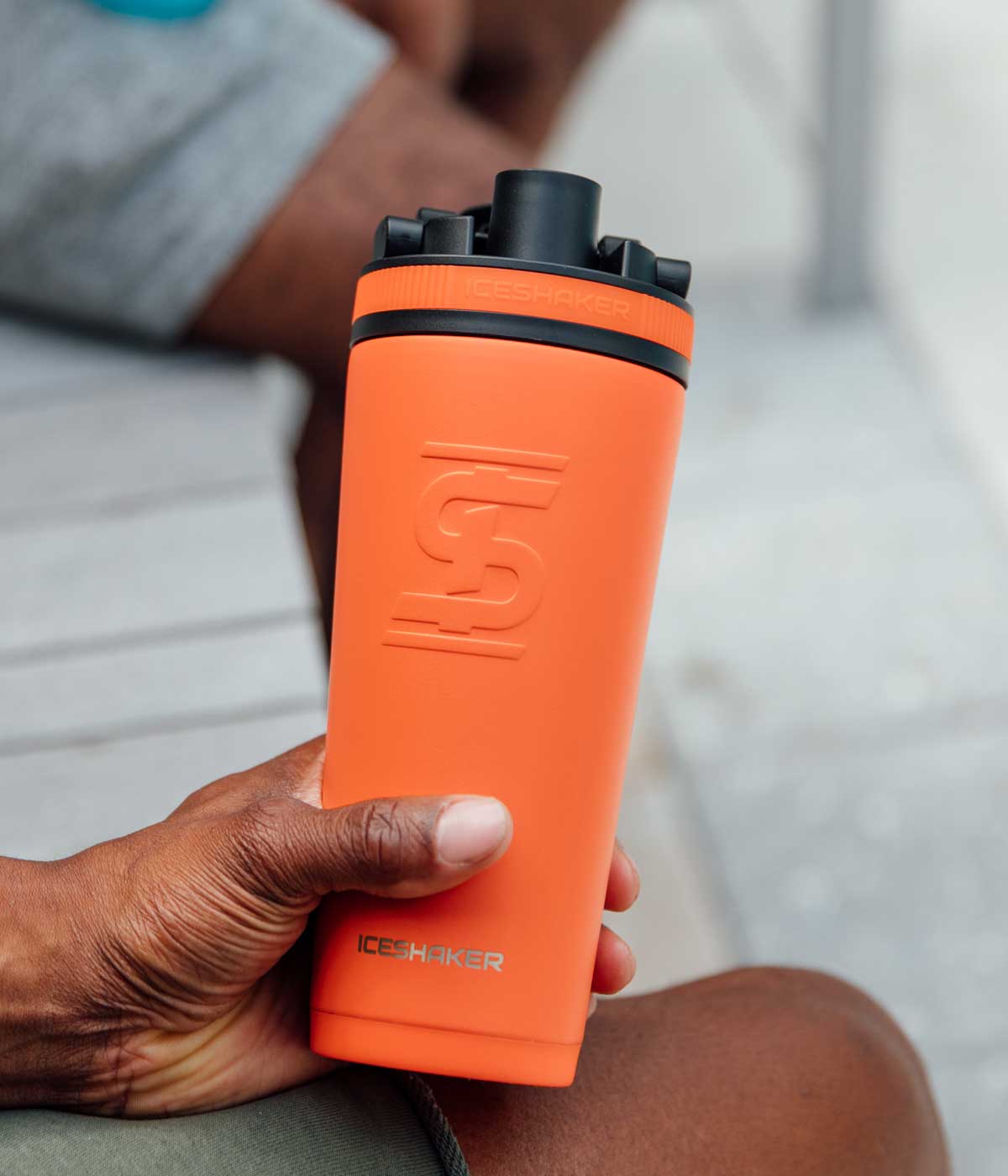 A close-up image of a man holding a orange-colored 36oz Ice Shaker.