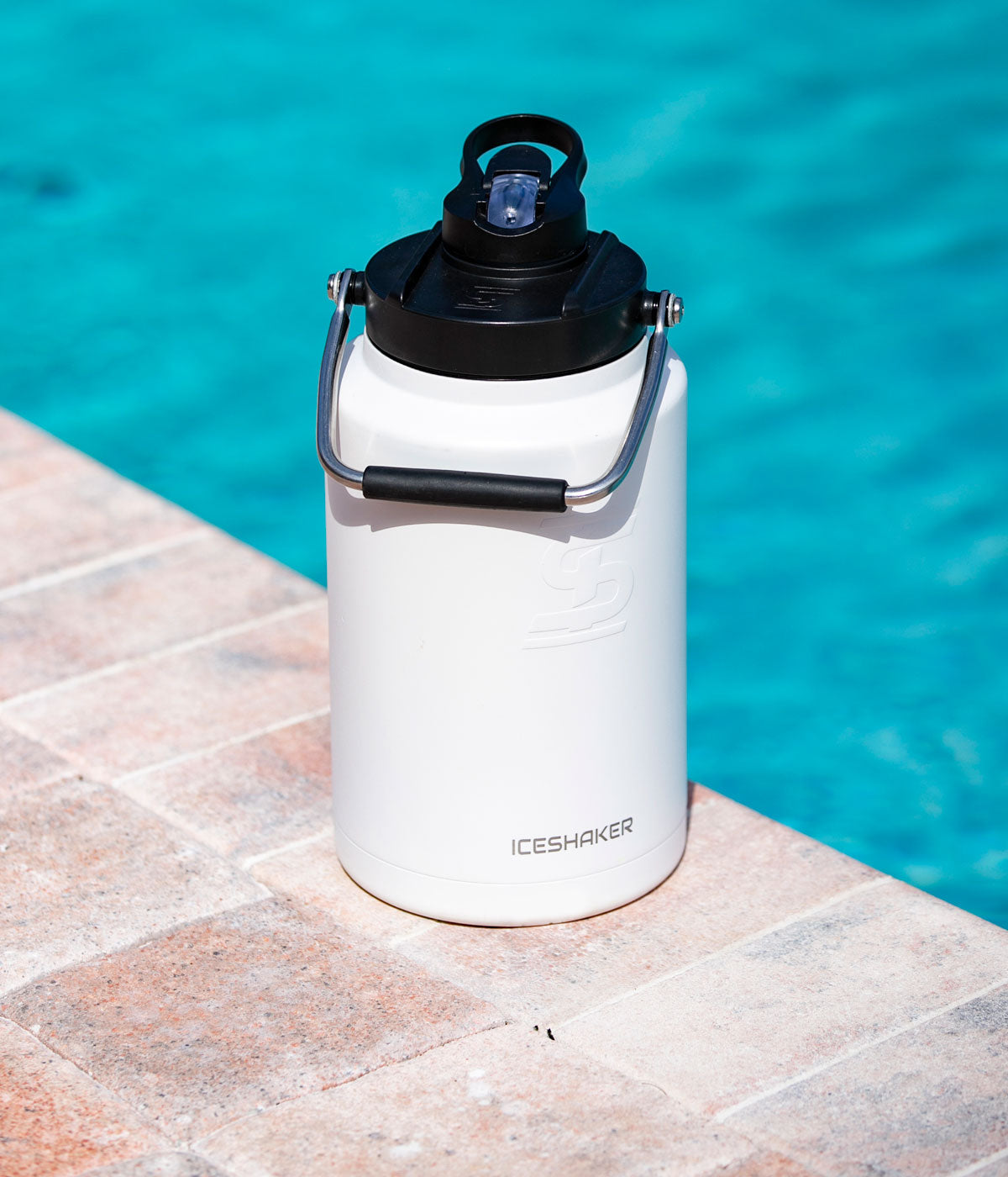 A white-colored Half Gallon Jug sits on concrete, next to an underground pool.