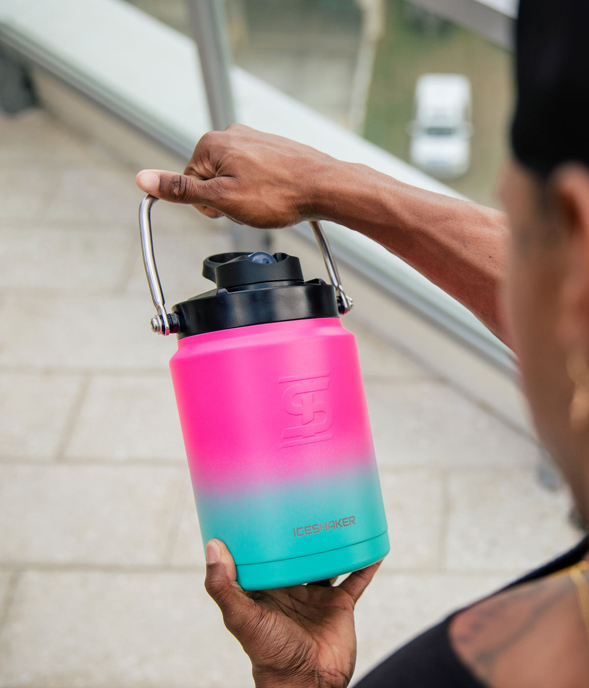 A man is holding a mint pink ombre-colored Half Gallon Jug by it's easy-carry handle.