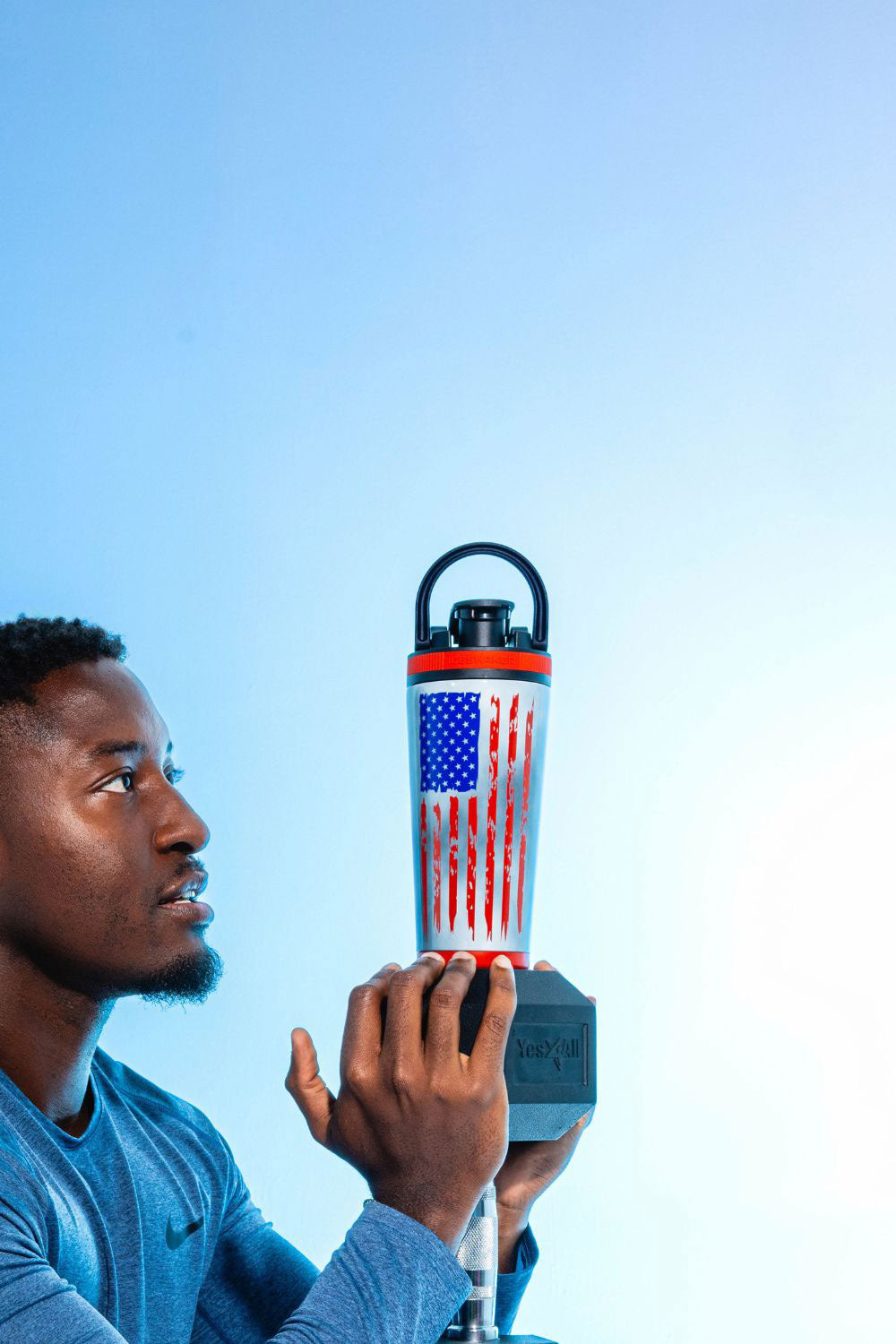 Man holding a water bottle with an American flag 4D Series 26oz Ice Shaker against a blue background