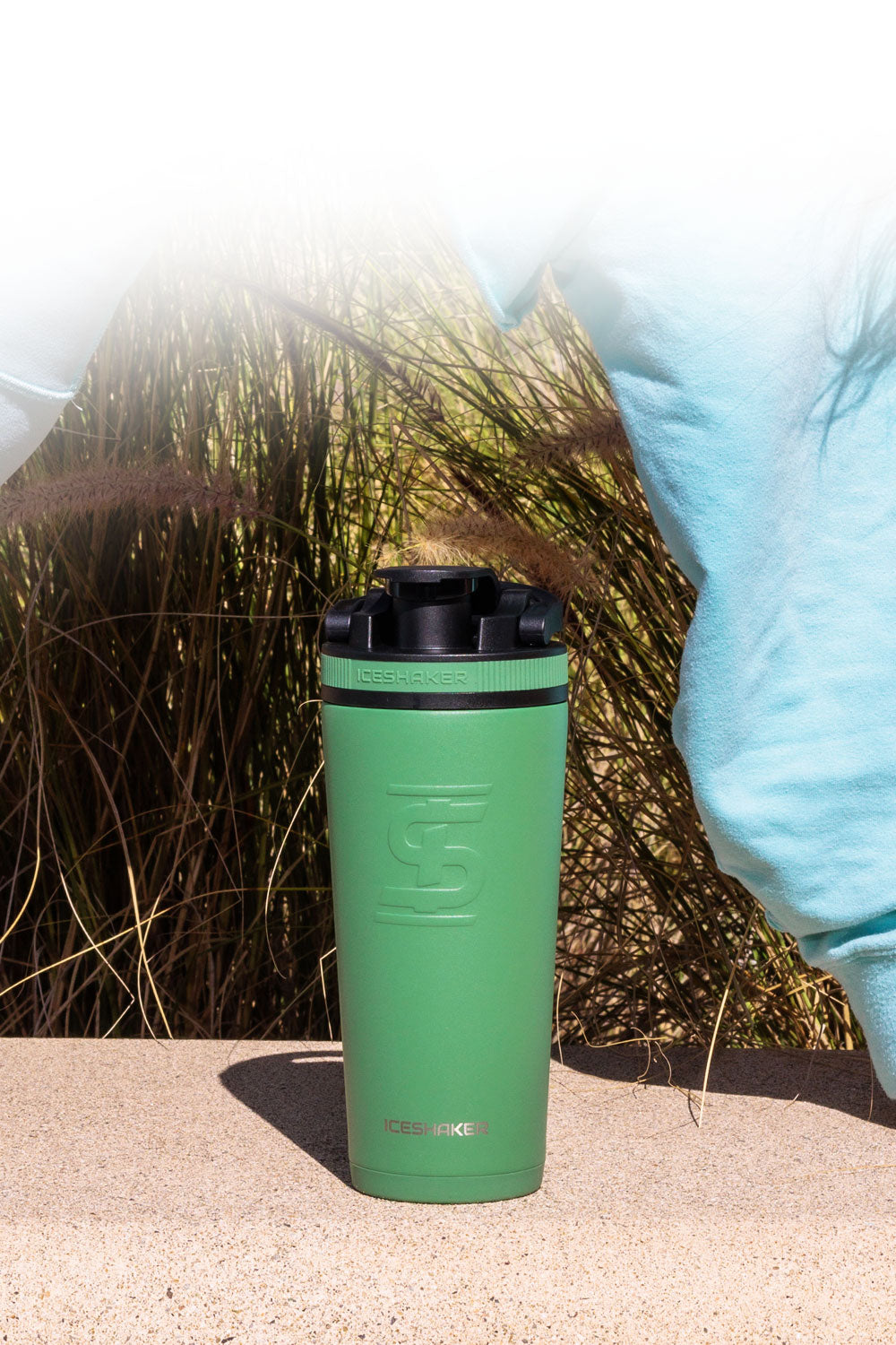 a Green Aura 26oz Ice Shaker outdoors in the sun.