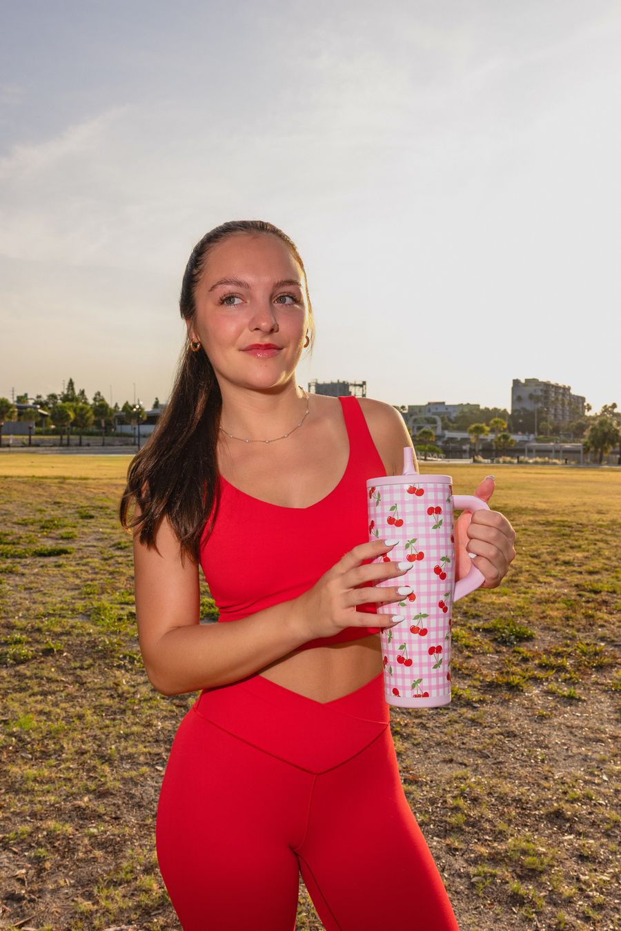 Woman in red activewear holding a Cherry Gingham tumbler